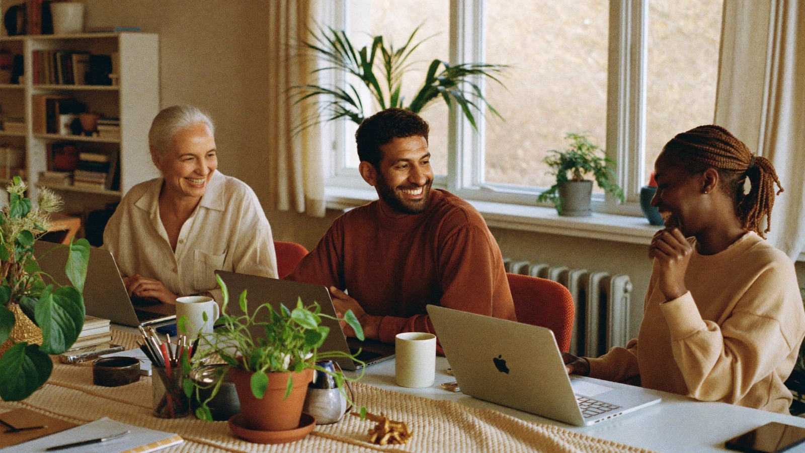 Three colleagues laughing around a studio table