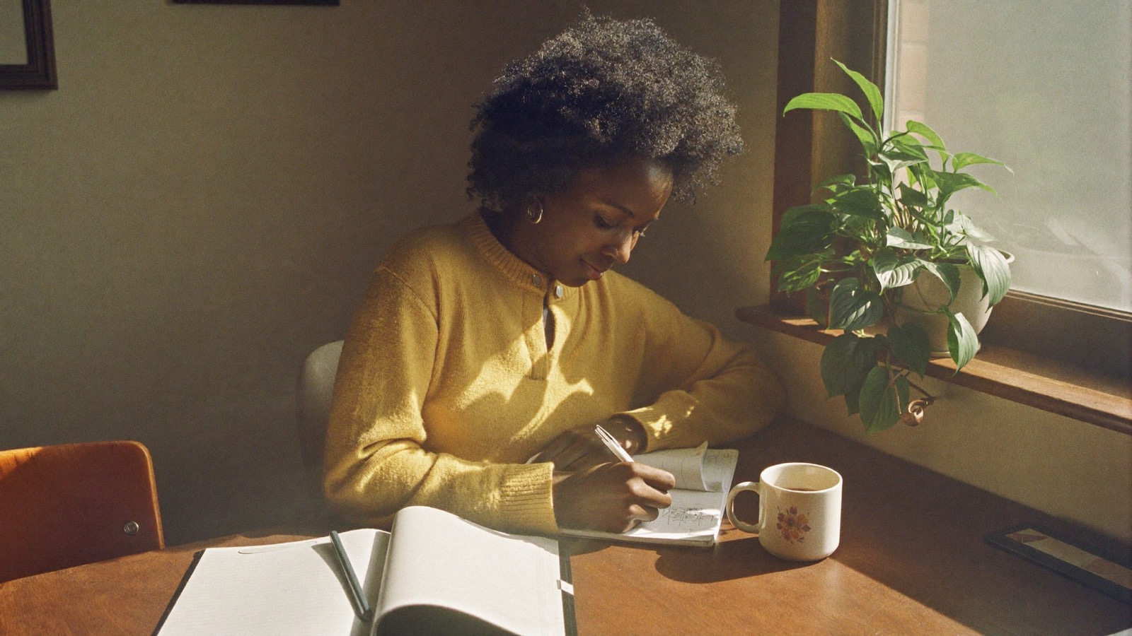 Writing a plan in a paper planner at a sunlit desk