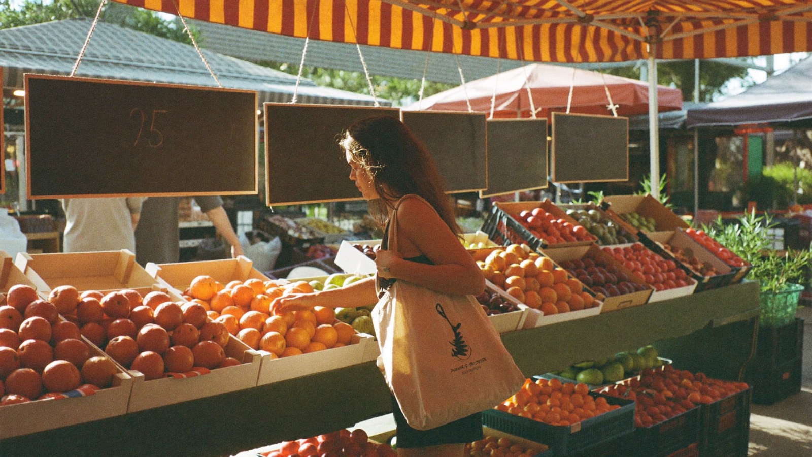 Choosing oranges at a farmers market stall