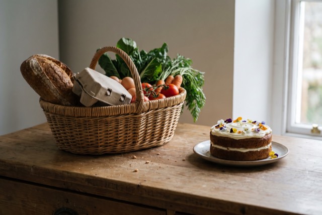 A basket of staples beside a small fancy cake