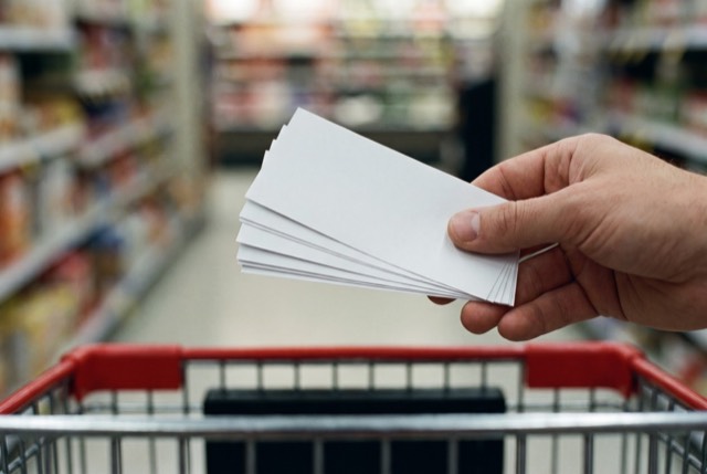 Holding coupons above a cart in the produce aisle