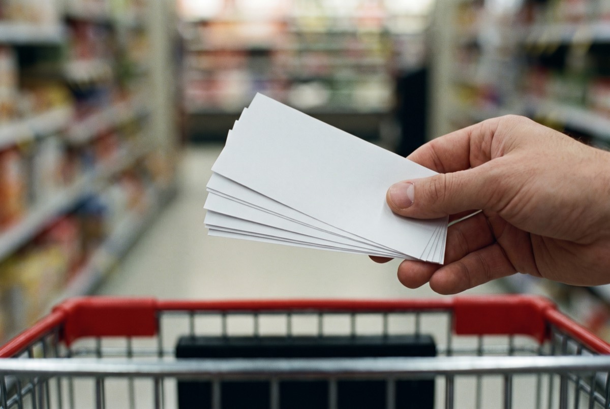 Holding coupons above a cart in the produce aisle