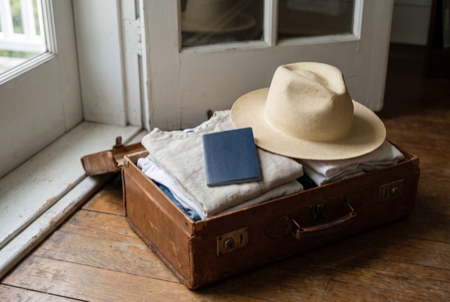 A packed suitcase with a sunhat by the door