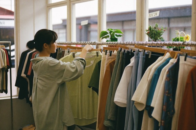 Browsing a rack in a bright thrift store