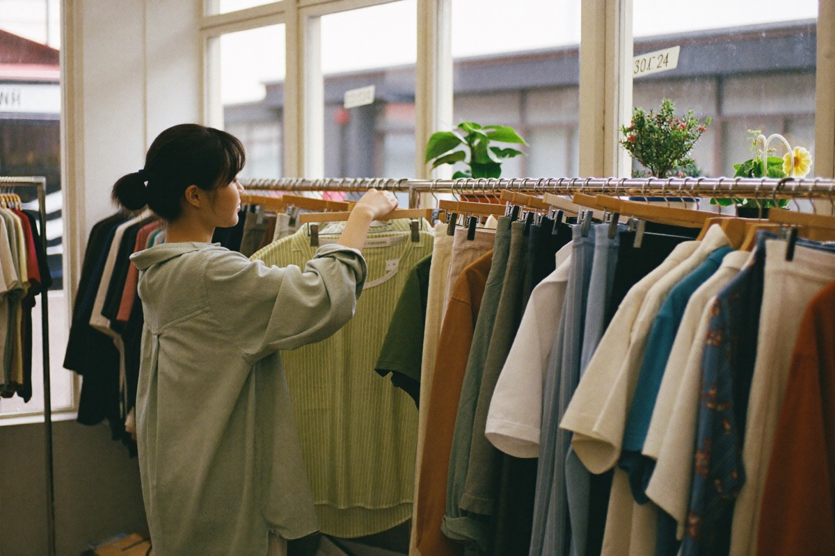 Browsing a rack in a bright thrift store